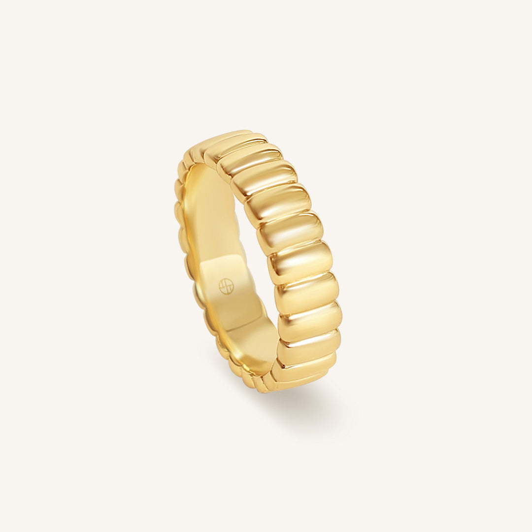Gold ring with a ribbed design on a white background