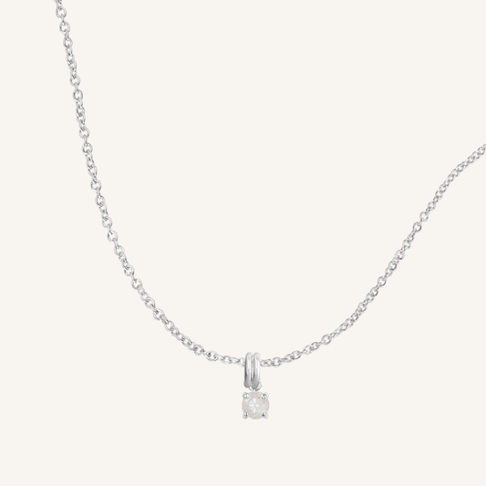 A silver charm necklace with a small moonstone pendant, isolated on a white background.