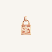 A rose-colored charm in the shape of a keylock with intricate patterns.