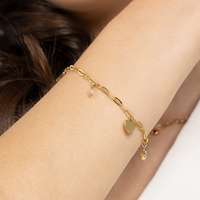 A gold-tone bracelet with paperclip links and multiple charms, including a heart, a star, and a letter, with an extender chain.