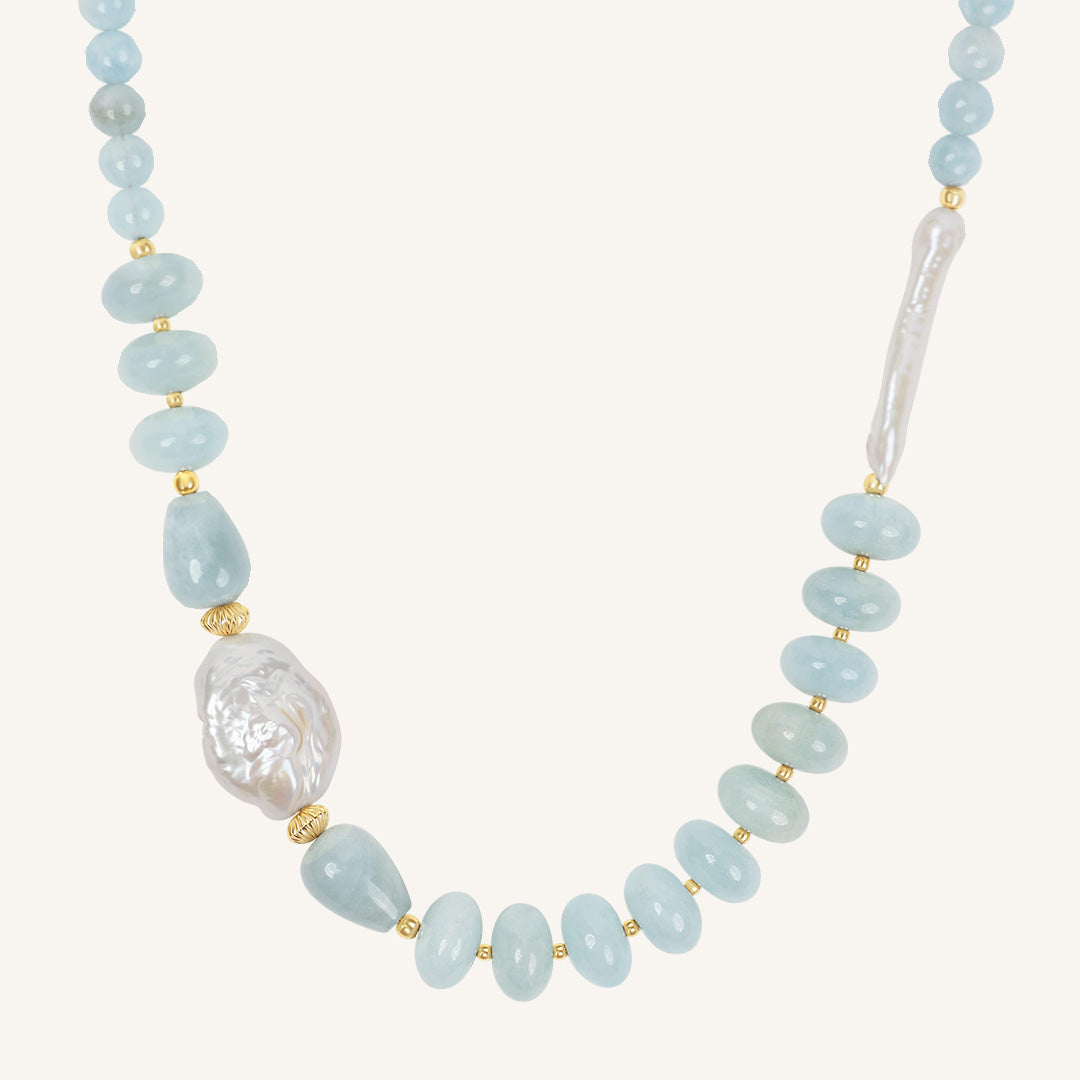 Necklace with light blue beads and a large pearl on a white background