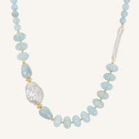 Necklace with light blue beads and a large pearl on a white background