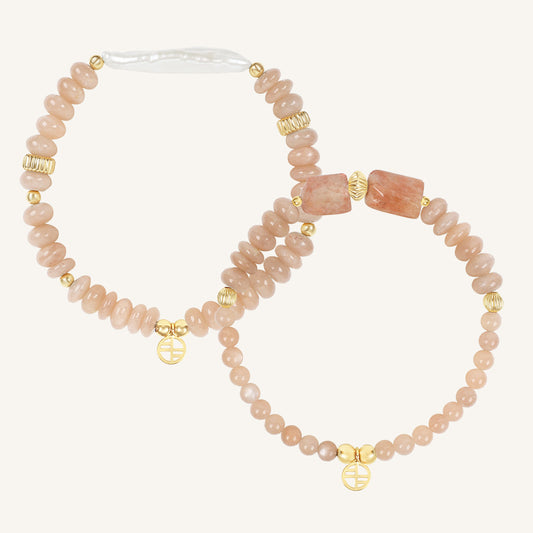 Set of two pink beaded bracelets with gold accents on a white background