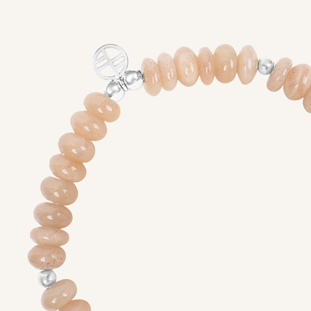 Bracelet with peach-colored beads and silver accents on a white background