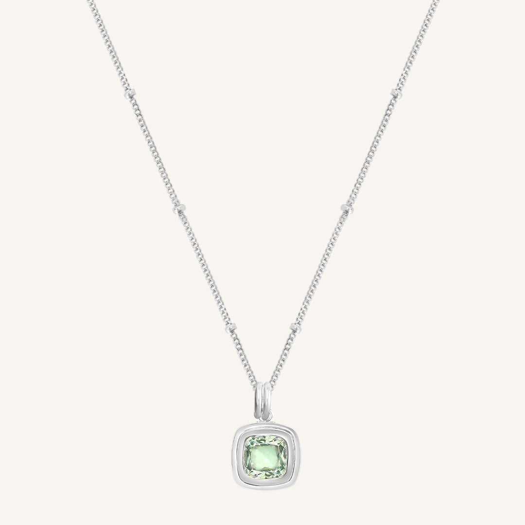 Silver necklace with a green gemstone pendant on a white background