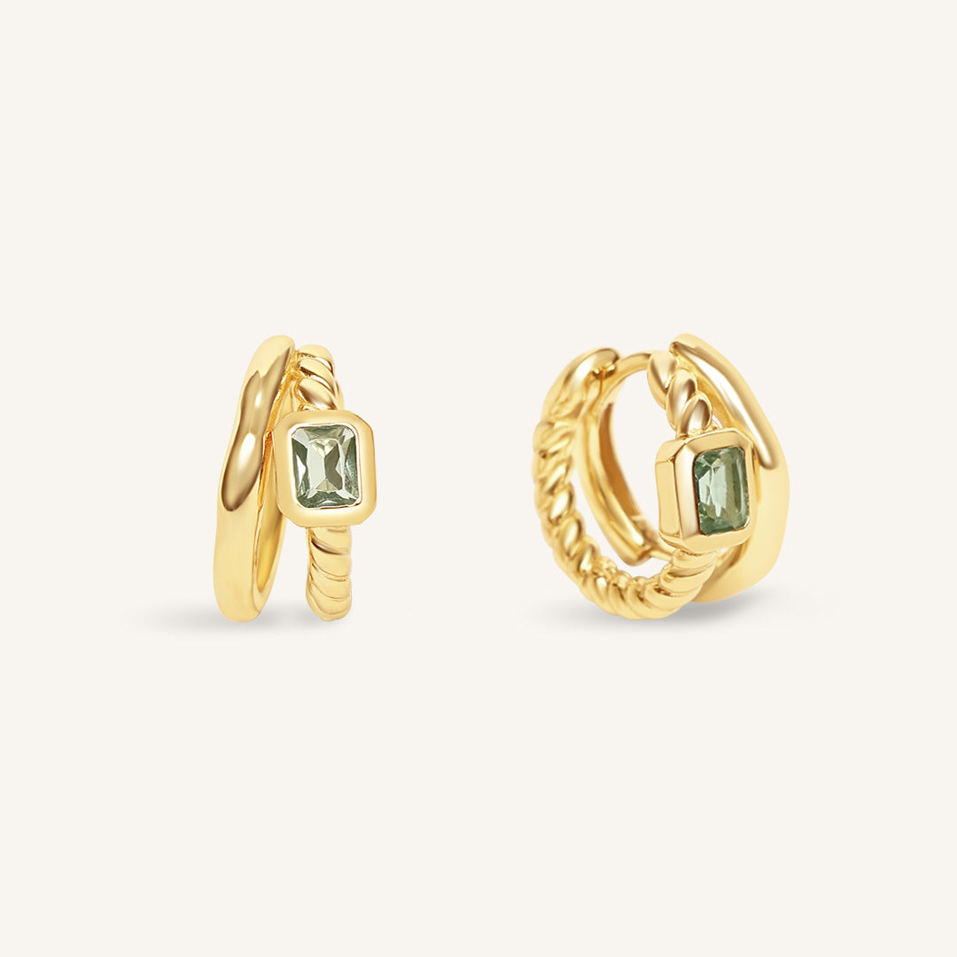 Gold hoop earrings with green gemstones on a white background