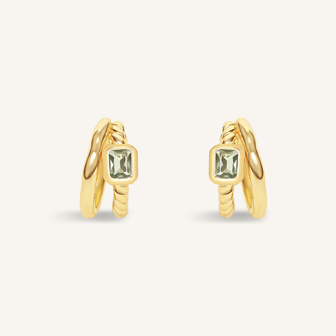 Gold hoop earrings with green gemstones on a white background