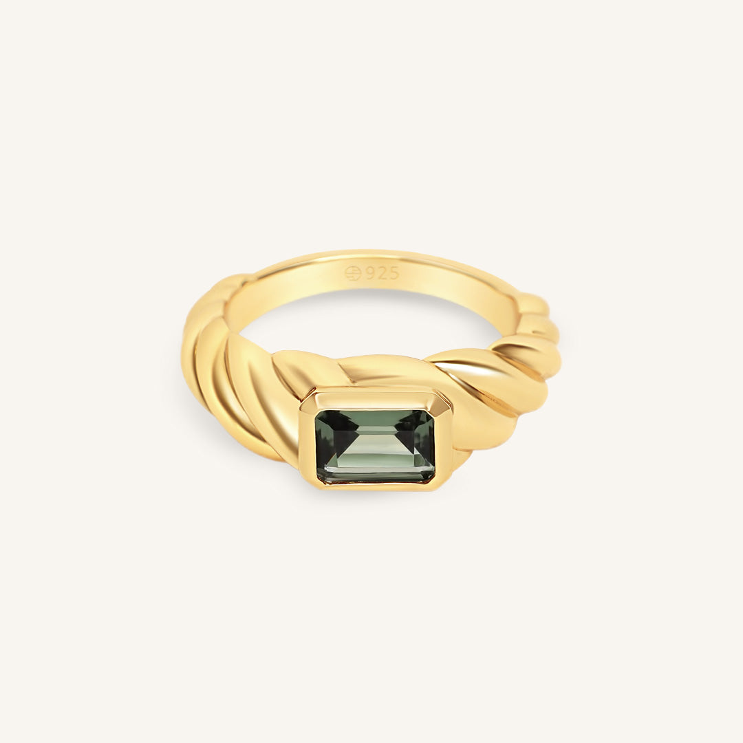 Gold ring with a green gemstone on a white background