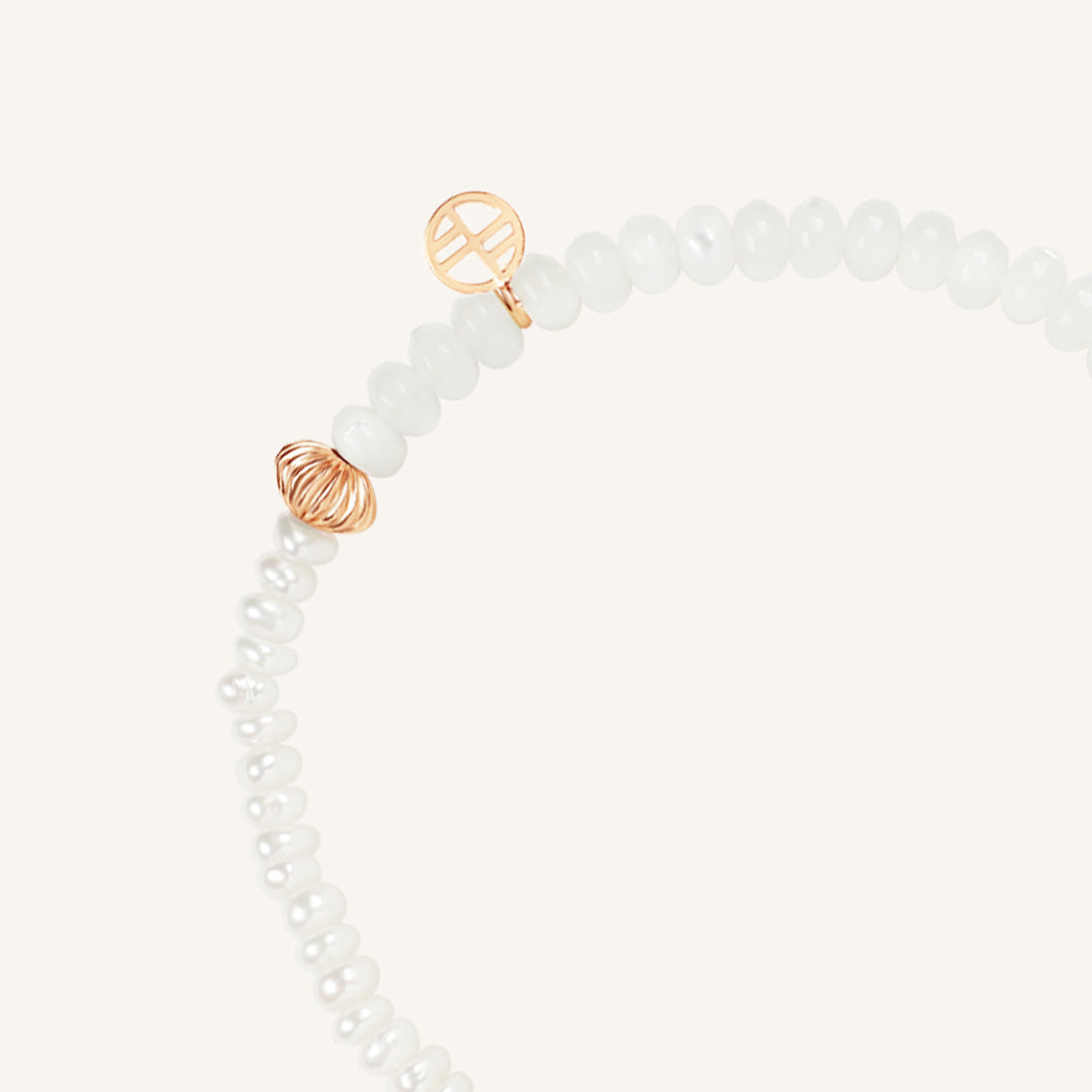 Bracelet with white beads and gold accents on a light gray background