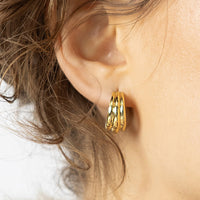 Gold hoop earrings on a light beige background