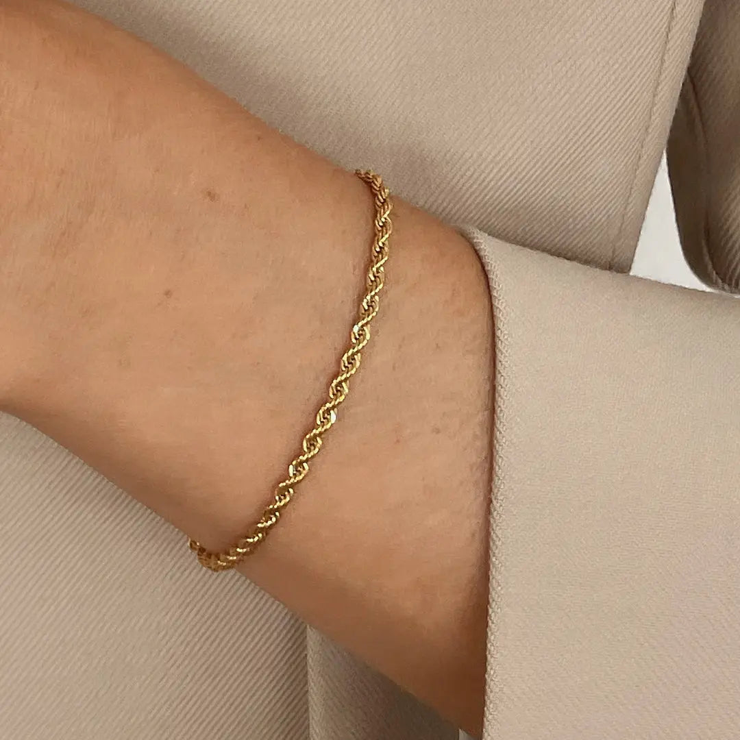A gold-tone rope bracelet with a extender chain, worn on wrist 