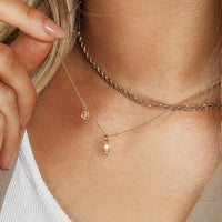 A small gold charm featuring a cubic zirconia and a floral design.