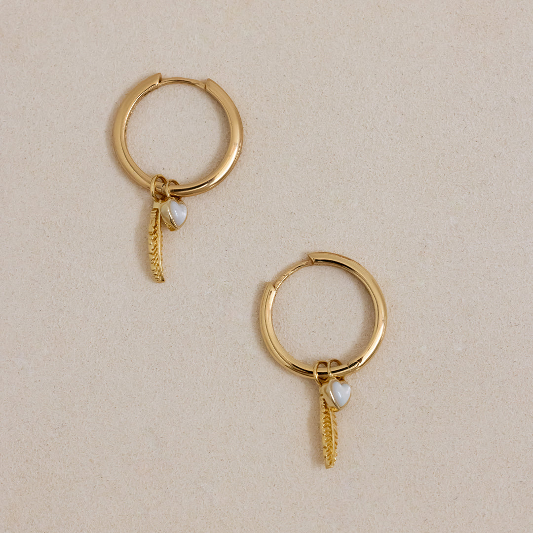 A set of two gold hoop charms with a feather design, on gold hoops