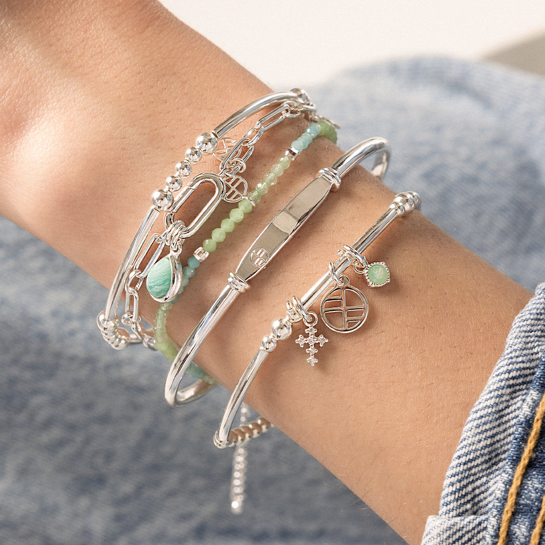 A silver-toned link bracelet, worn on models wrist, stacked with other bracelets