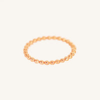 A rose gold coloured stacking ring with a simple, elegant design featuring small, uniform beads around its circumference.