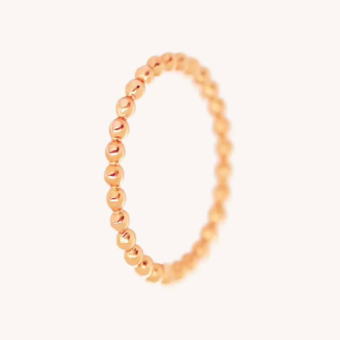 A rose gold coloured stacking ring with a simple, elegant design featuring small, uniform beads around its circumference.