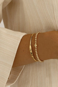 A gold bracelet with a beaded design and an engraveable bead